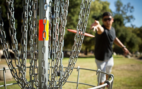 Disc golfer releases disc towards the basket for a successful putt.